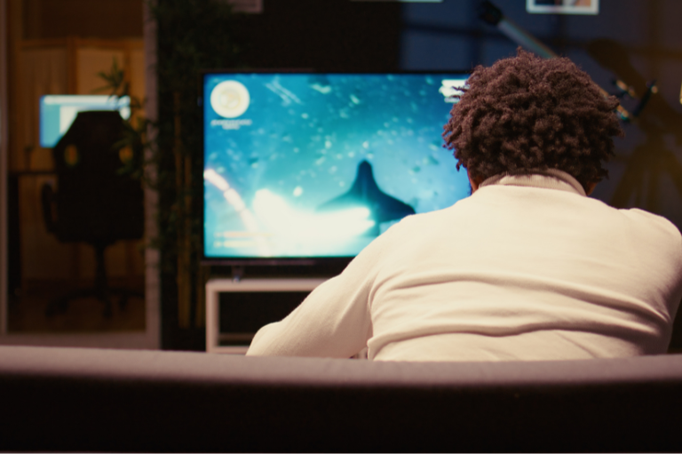 Foto mostra um homem em frente à TV