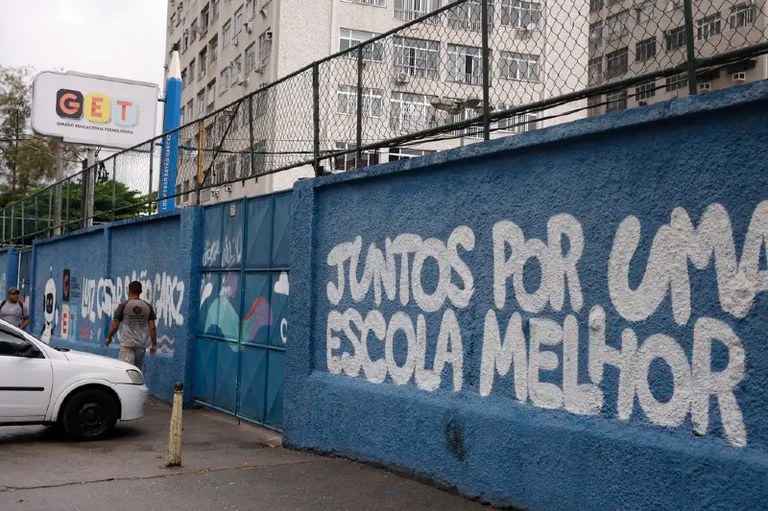 Foto mostra escola pública fechada na Vila Cruzeiro após operação. No muro azul está escrito em branco Juntos por uma escola melhor