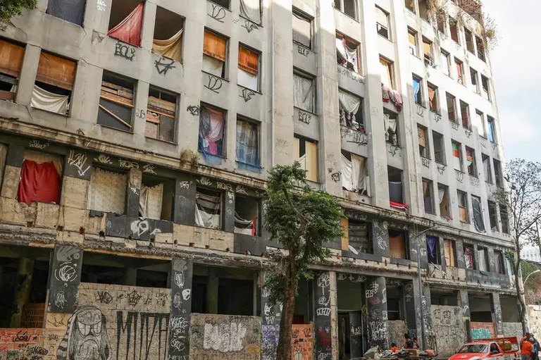 Foto mostra o prédio de sete andares abandonado, com aspecto precário. A fachada está pichada