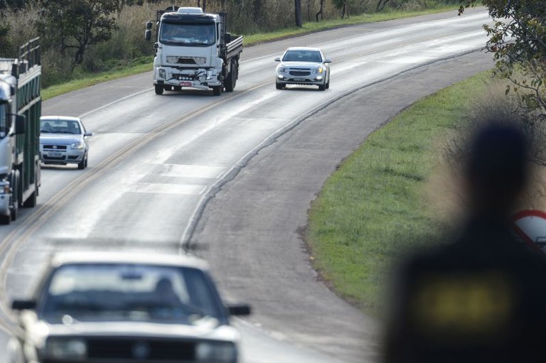 Foto mostra carros e caminhões passando por uma rodovia