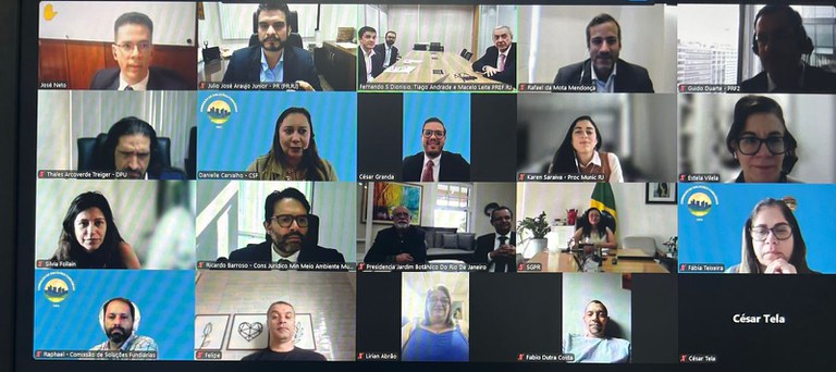 Captura de tela de uma reunião virtual com 22 participantes distribuídos em uma grade de videoconferência. Algumas pessoas estão sozinhas em seus enquadramentos, enquanto outras aparecem em grupos no mesmo ambiente. Entre os participantes, há homens e mulheres de diferentes idades, alguns usando fones de ouvido e outros com microfones desligados, indicados pelo ícone vermelho. O fundo varia entre escritórios, salas de casa, bandeiras do Brasil, paredes lisas e planos virtuais com logotipos institucionais. Cada janela exibe o nome e, em alguns casos, a instituição ou função do participante.