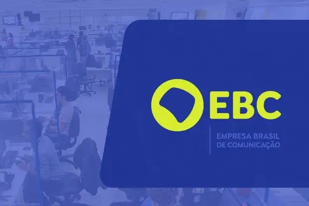 Imagem com uma fotografia de uma sala de redação jornalística, desfocada e ao fundo, em tons de azul, e uma figura geométrica à direita, em azul, com a marca da EBC em amarelo e o nome "Empresa Brasil de Comunicação" em azul claro.