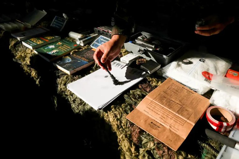 Foto mostra kits periciais em cima de uma estrutura.