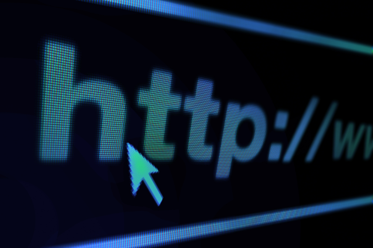 Foto de close-up em nível de pixel de uma tela escura, mostrando o início de um endereço web, "http://www", na barra de endereços de um navegador, com um cursor de seta apontando para as letras.