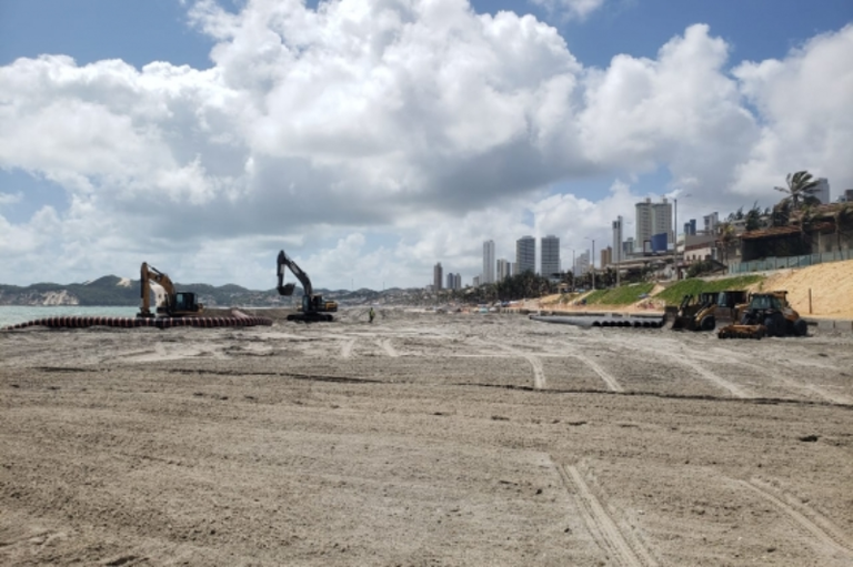 Foto mostra quatro retroescavadeiras em área de areia da Praia de Ponta Negra