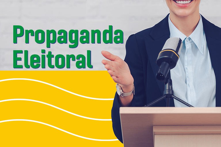 Imagem em formato horizontal sobre propaganda eleitoral. À direita, vê-se o torso de uma pessoa sorridente usando terno escuro e camisa social clara, posicionada atrás de um púlpito de madeira com um microfone fixado à sua frente e a mão direita estendida em um gesto de oratória. O fundo da imagem é dividido em duas partes: o topo é cinza claro com textura de tijolos, e a metade inferior é amarela com linhas onduladas brancas. Do lado esquerdo, sobrepostos ao fundo, destacam-se os textos "Propaganda" em verde e, logo abaixo, "Eleitoral" também em verde, ambos destacados em caixa-alta e negrito com contornos suaves em azul.