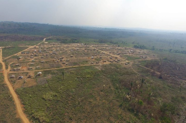 Foto mostra uma grande área devastada entre uma área maior, de floresta.
