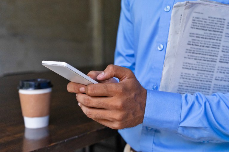 Foto mostra homem lendo uma notícia no celular