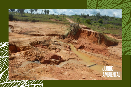 Uma área de terra arrasada e erodida após o rompimento de um dique, mostrando crateras, solo avermelhado exposto e filetes de água barrenta, inserida em uma moldura verde com grafismos de folhas e o texto "JUNHO AMBIENTAL".