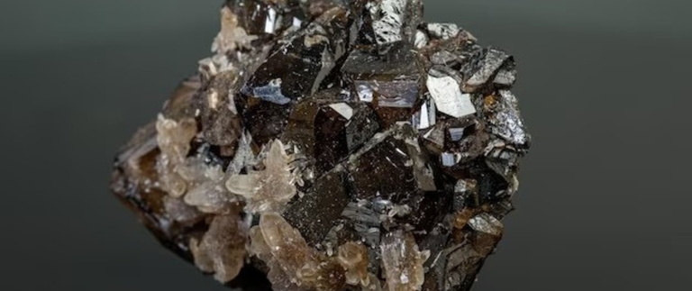 Foto mostra saco cheio de cassiterita. Há uma faca dourada cravada no material