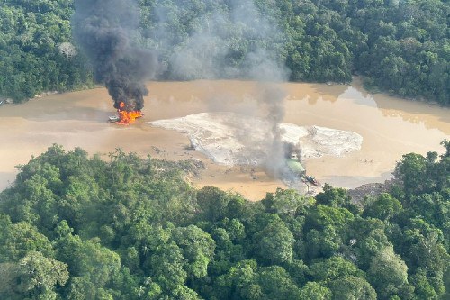 Foto aérea mostra área de garimpo ilegal na Amazônia. Equipamentos são queimados na beira de um rio