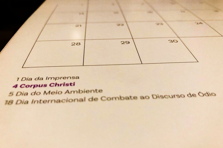 Imagem de um calendário com o mês de Junho de 2025, e em destaque, a informação de que Corpus Christi, em roxo, dia 4, é feriado