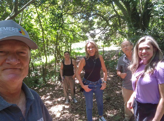 Integrantes do FGCIA com o senhor Olímpio dentro da agrofloresta em Nova Santa Rita sorriem para a câmera