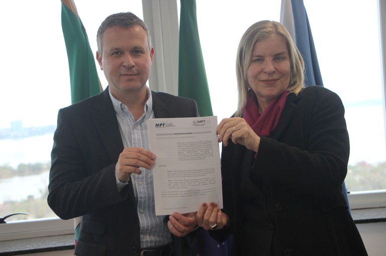 Procurador-chefe do MPF/RS Felipe Müller e a procuradora-chefe da Procuradoria Regional do Trabalho da 4ª Região (PRT4), Denise Maria Schellenberger Fernandes, seguram diante de si o documento assinado do protocolo de intenções para a construção de uma sede conjunta no município de Santo Ângelo