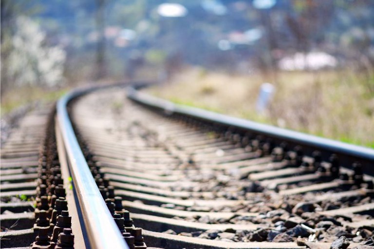 Trilho de trem com curva para a direita ao fundo