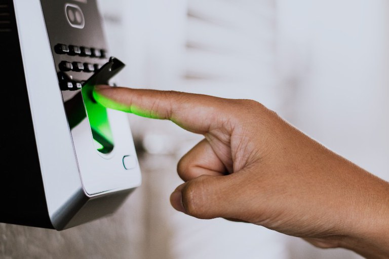 Foto mostra uma pessoa colocando o dedo em um dispositivo de ponto eletrônico