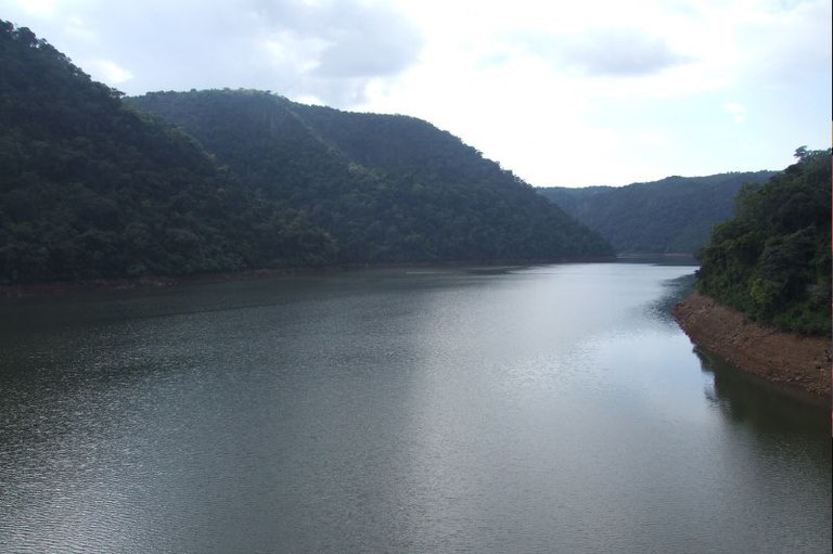 Foto mostra trecho do leito do Rio Uruguai, com o rio no centro, montes verdes no entorno e um pouco do céu, claro e com algumas nuvens brancas.