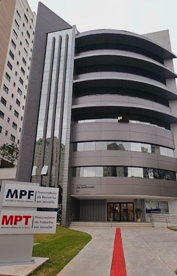 A foto da fachada de um prédio de seis andares. Do lado esquerdo, um totem com as logomarcas do MPF e do MPT.