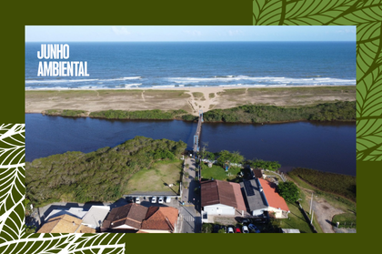 Vista aérea de uma praia e um rio escuro cruzado por uma pequena ponte, com casas em primeiro plano e o texto "JUNHO AMBIENTAL" no canto superior esquerdo.