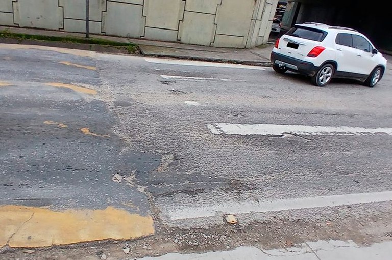 Imagem mostra uma faixa de pedestre apagada e um carro branco passando