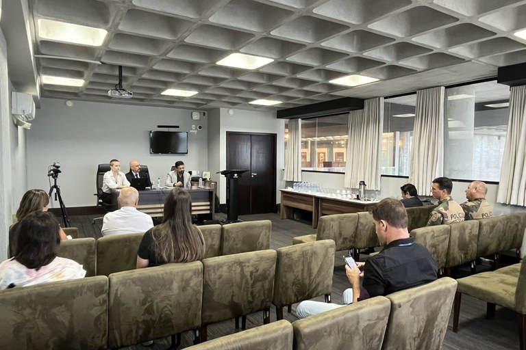 Representantes do MPF, IMA e CPMA discutem combate aos crimes contra espécies da flora ameaçadas de extinção em SC, em 28/01/2025. Foto de uma sala de auditório com pessoas sentadas na platéia e, ao fundo, dois homens e uma mulher sentados à mesa do evento.