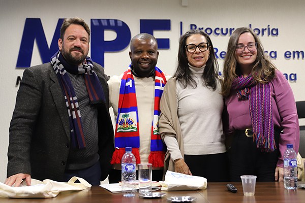 O diretor do Centro de Direitos Humanos e Cidadania do Imigrante, Paulo Illes, o economista Jean Rosier, a procuradora regional da República Daniele Escobar e a diretora da Círculos de Hospitalidade, Bruna Kadletz, posam para foto. Ao fundo da imagem, a logomarca do MPF.