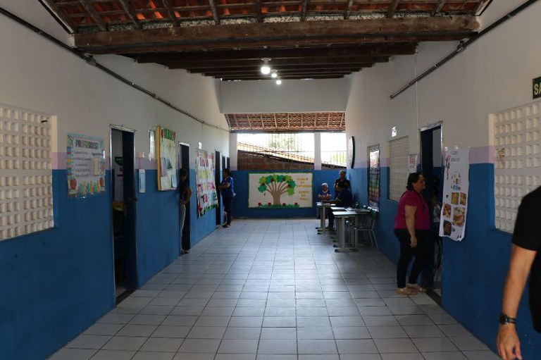 Foto do corredor de uma escola mostra portas azuis para salas de aula