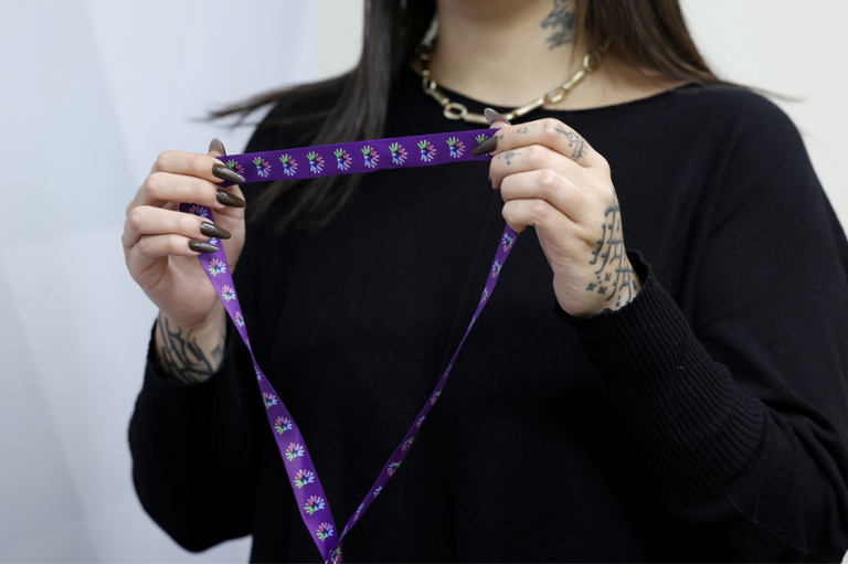 Foto mostra uma mulher segurando um cordão multicolorido que identifica pessoas com doenças raras