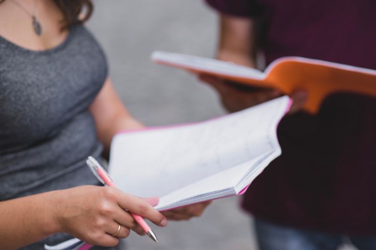 Foto de estudantes segurando um cadernos