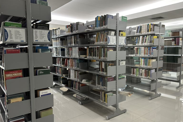 Imagem de três estantes com livros disponíveis para doação