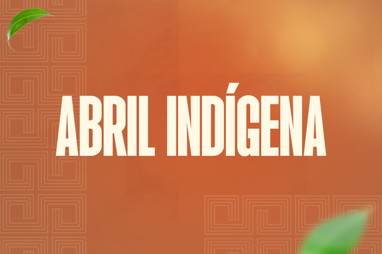 A imagem tem um fundo laranja com padrões geométricos suaves. No centro, há um texto branco grande que diz "ABRIL INDÍGENA". Folhas verdes decoram os cantos superior esquerdo e inferior direito.