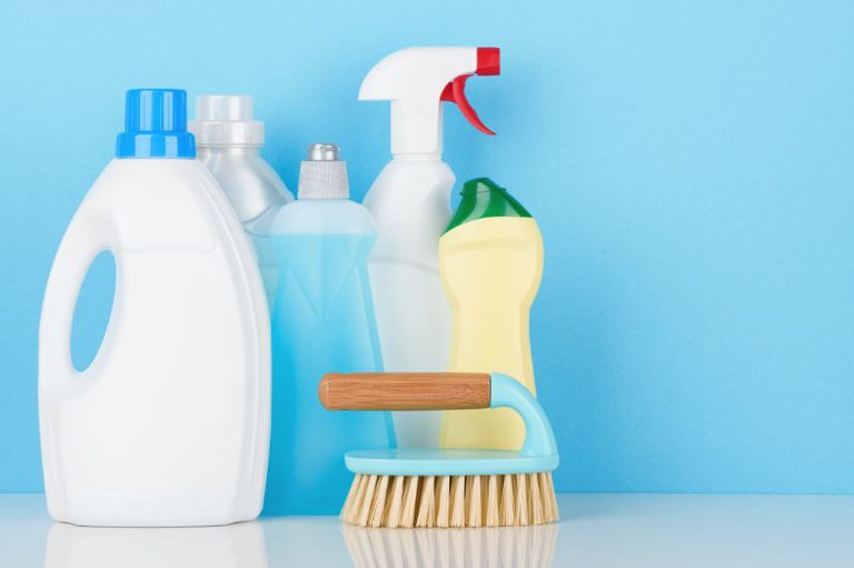 Foto mostra frascos de produtos de limpeza e uma escovinha