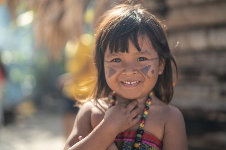 Imagem mostra menina indígena com rosto pintado sorrindo