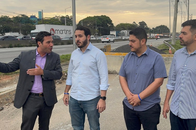 Imagem mostra grupo de pessoas conversando à beira de uma rodovia