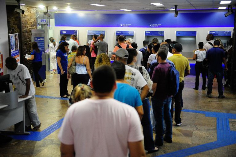 Foto mostra uma agência da Caixa com filas nos caixa eletrônicos