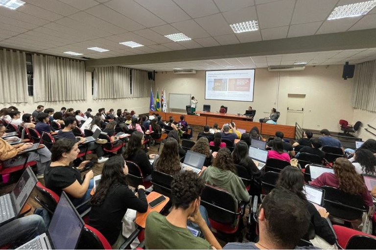Imagem mostra auditório com pessoas que assistem a uma apresentação