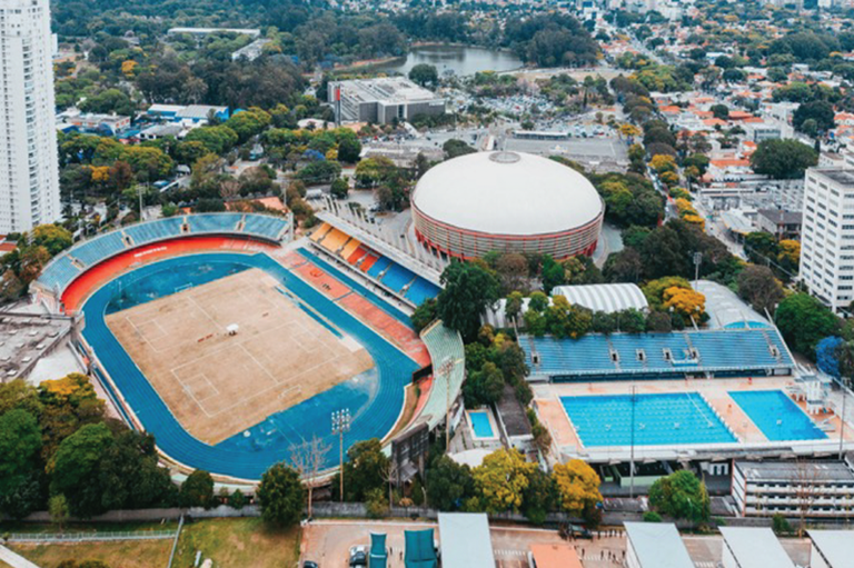 imagem aérea mostra ginásio esportivo, um estádio e piscina com arquibancadas