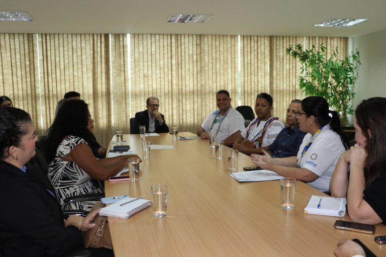 Foto dos participantes da reunião reunidos em volta de uma mesa