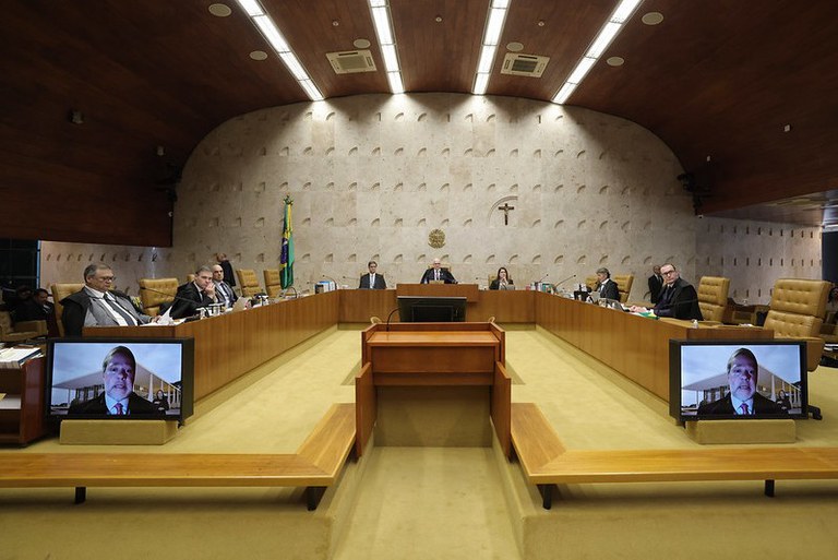 Foto da sessão plenária do STF de 23 de outubro. É possível ver os ministros, o procurador-geral da República, Paulo Gonet Branco. Em primeiro plano, na TV (por videoconferência), é possível ver o ministro Dias Toffoli