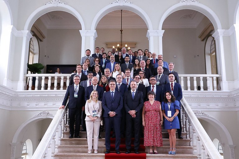 Foto oficial do evento, com autoridades (a maioria homens) em pé numa escadaria