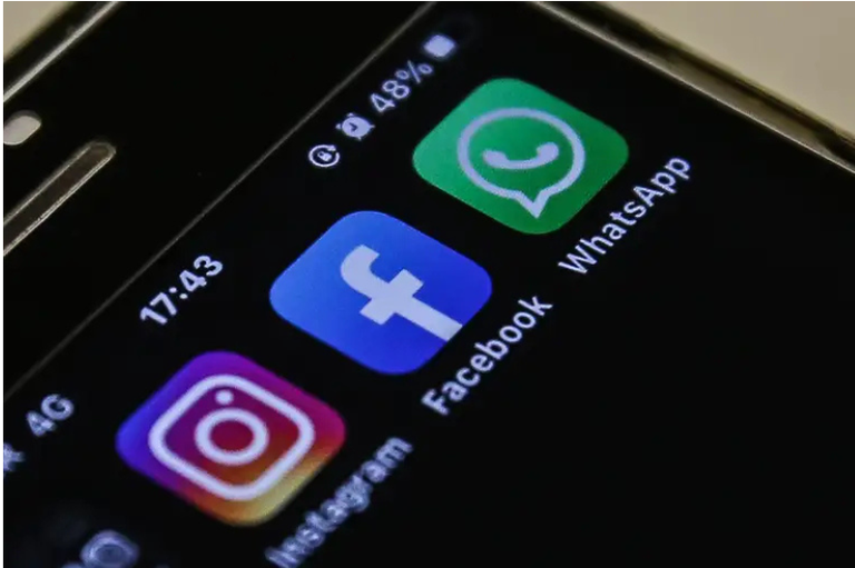 Close da ecrã de um smartphone mostrando os ícones dos aplicativos Instagram, Facebook e WhatsApp alinhados sobre um fundo escuro.