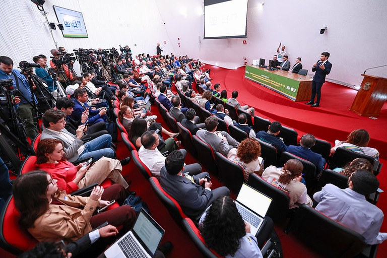 Cerimônia de Verificação dos Sistemas Eleitorais e Emissão da Zerésima no TSE. Em auditório lotado com piso vermelho no tribunal, n palco, um homem de terno fala ao microfone diante de uma mesa de autoridades; na plateia, pessoas assistem, usam notebooks e cinegrafistas registram o evento.