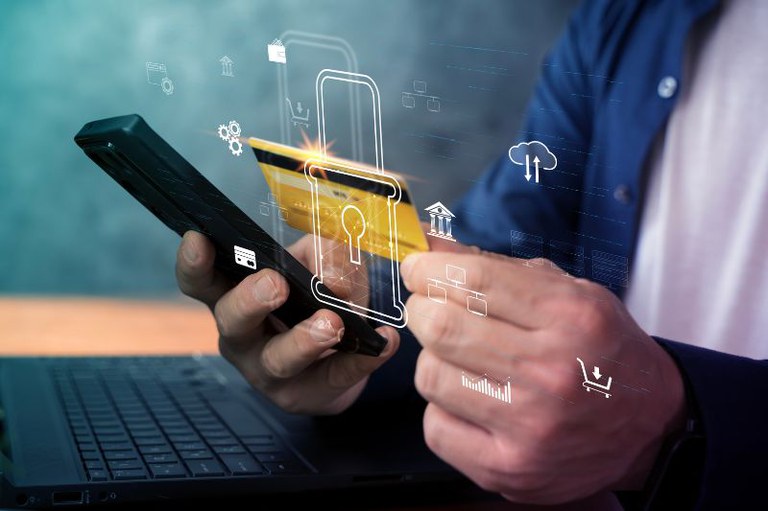 Imagem de uma pessoa no computador segurando um cartão de crédito e vários ícones de cadeado, financiamento, compras, investimento, etc