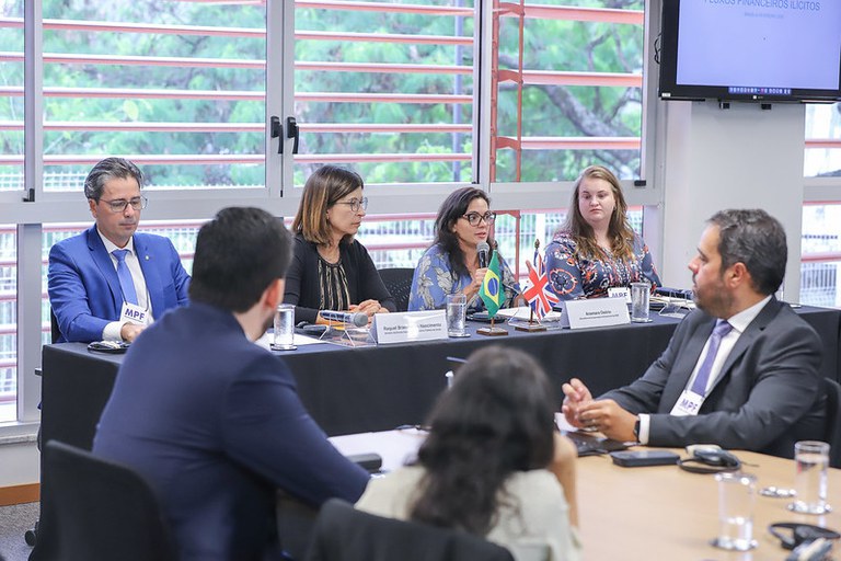 Imagem da mesa de abertura do curso com todos os palestrantes sentados e os participantes assistindo