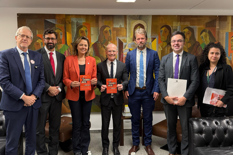 Imagem de todas as autoridades que participaram da reunião de pé segurando documentos