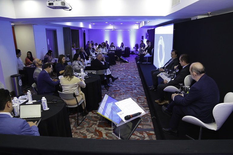 Participantes do evento reunidos em mesas de discussão.