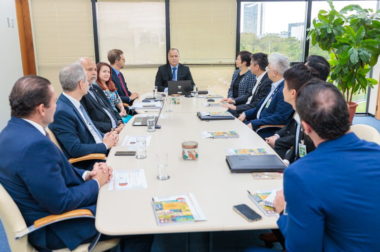 Imagem da reunião com a comitiva de Hong Kong com todas as autoridades sentadas em volta de uma mesa oval
