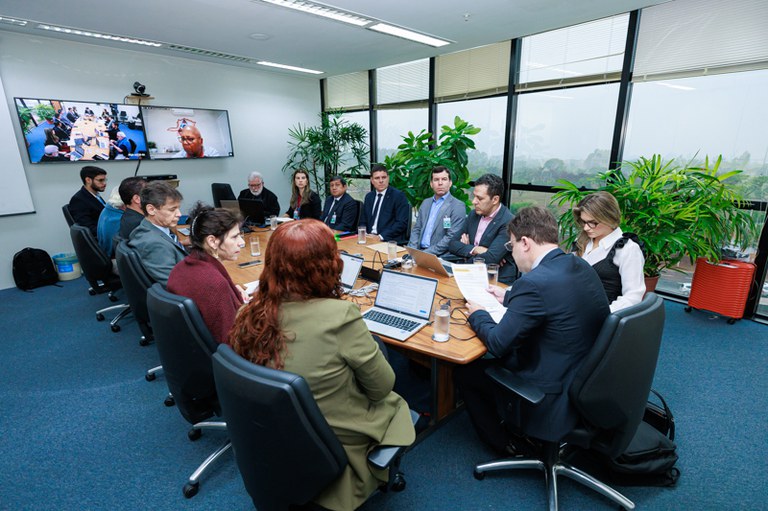 foto de mesa de reuniões com várias pessoas ao redor