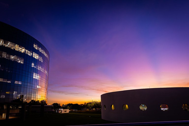 Foto do pôr-do-sol enfocando um dos prédios espelhados da PGR.