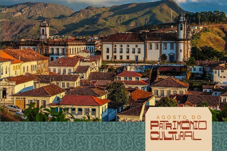 Vista panorâmica de uma cidade histórica com casario de telhados vermelhos, grandes edifícios coloniais e montanhas ao fundo. Na parte inferior, destaca-se um banner com a inscrição "Agosto do Patrimônio Cultural".